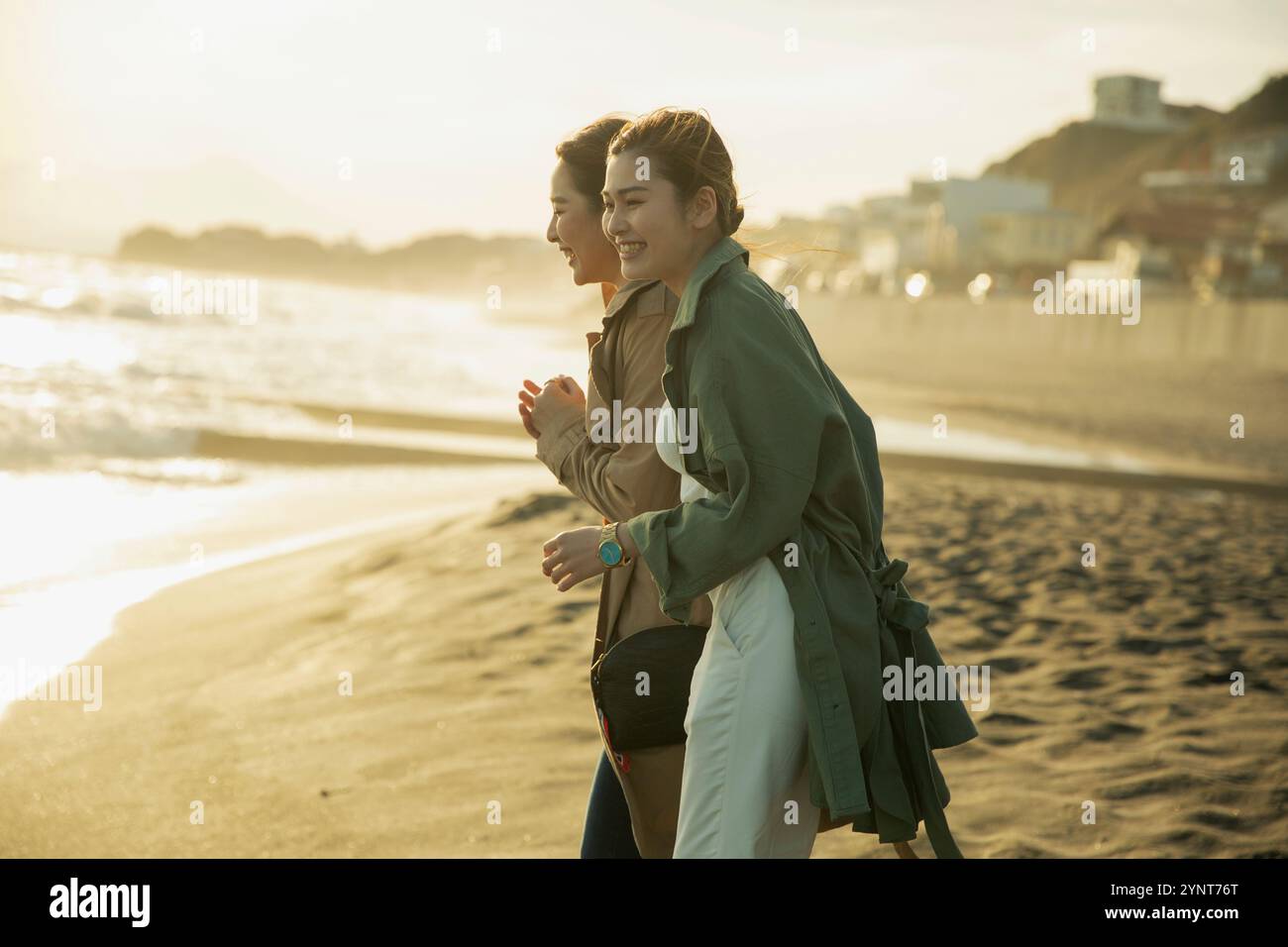 Two women in their 20s enjoying a walk in the surf Stock Photo - Alamy