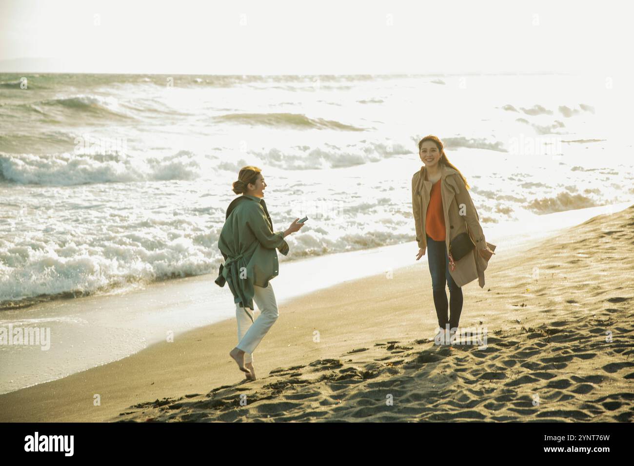 Two women in their 20s enjoying a walk in the surf Stock Photo - Alamy