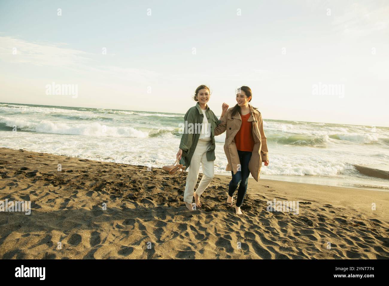 Two women in their 20s enjoying a walk in the surf Stock Photo - Alamy