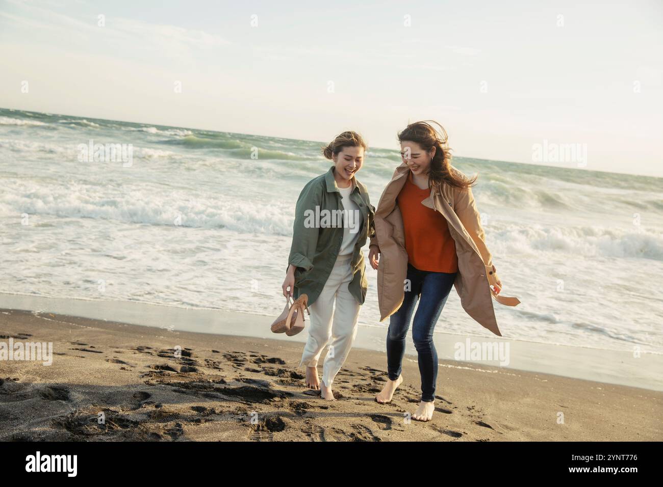 Two women in their 20s enjoying a walk in the surf Stock Photo - Alamy