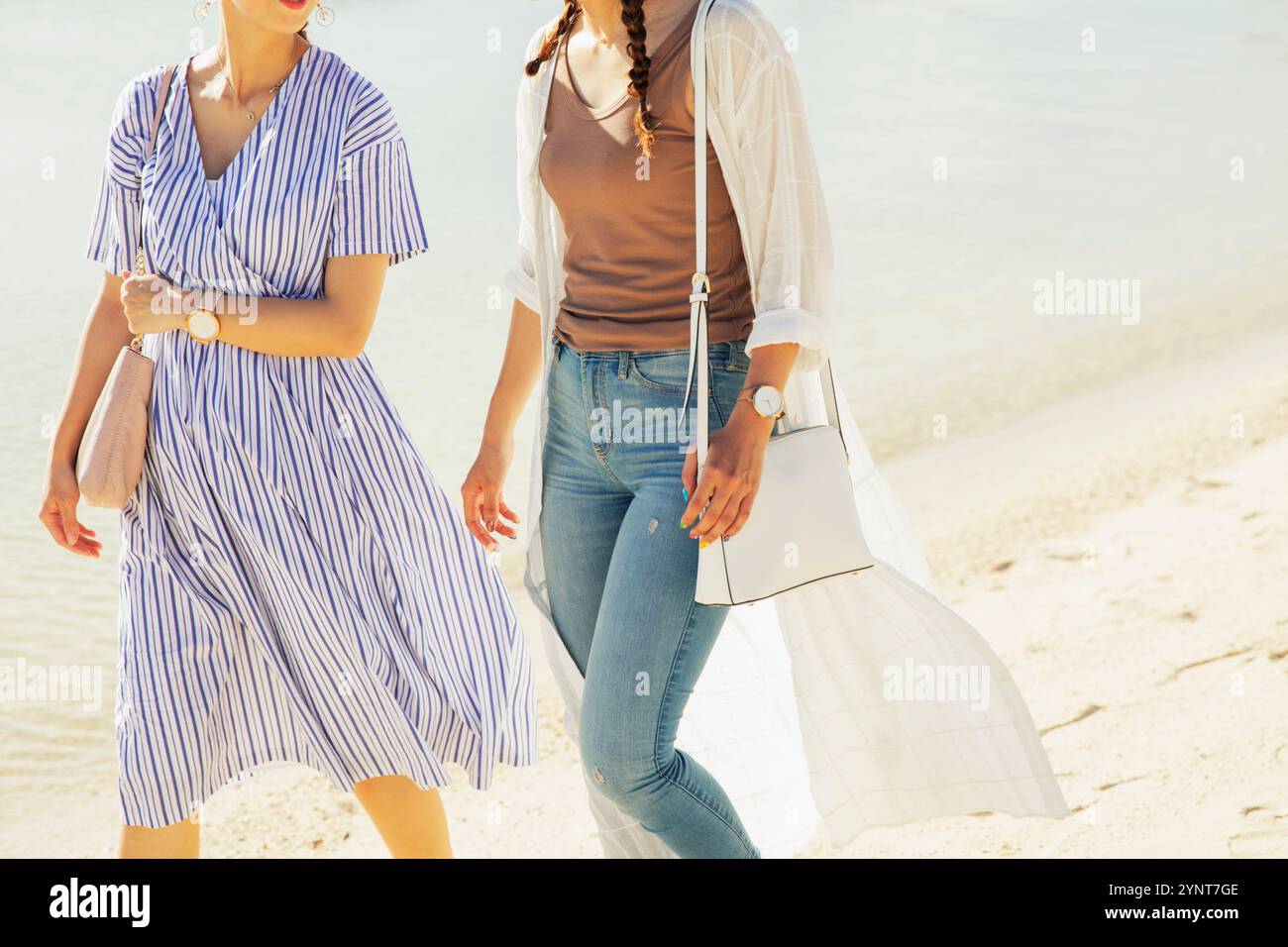 Two women in their 20s walking on a sandy beach Stock Photo - Alamy