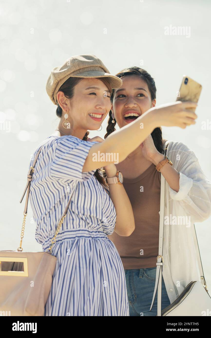 Two women in their 20s taking photos in the sea Stock Photo - Alamy