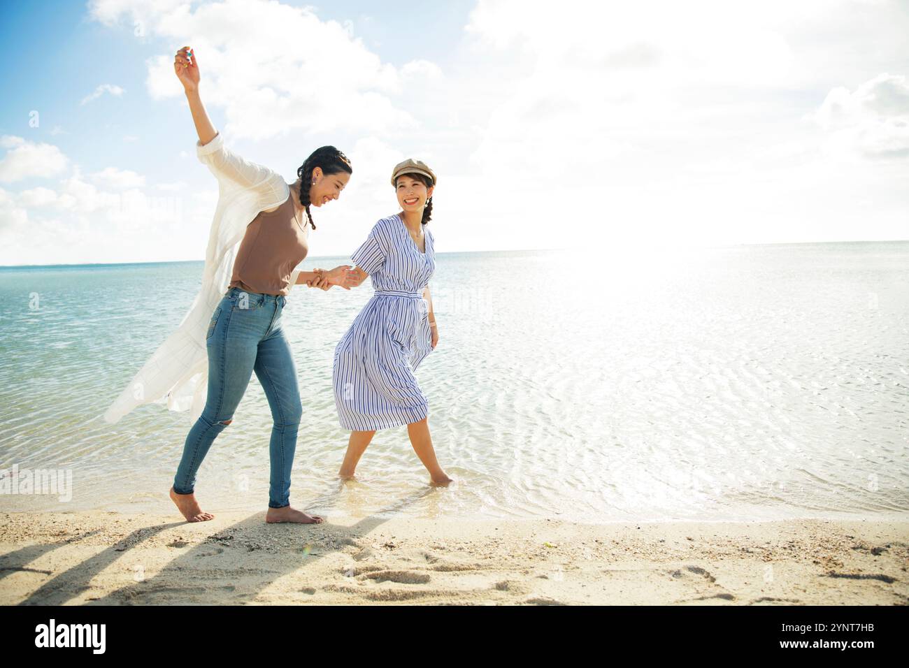 Two women in their 20s walking on a sandy beach Stock Photo - Alamy