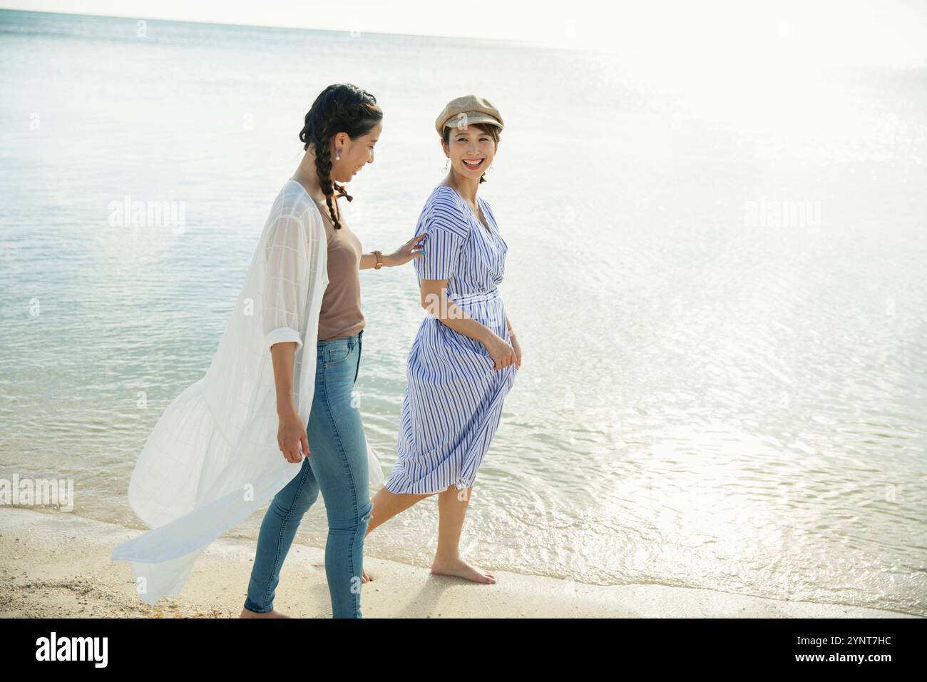 Two women in their 20s walking on a sandy beach Stock Photo - Alamy