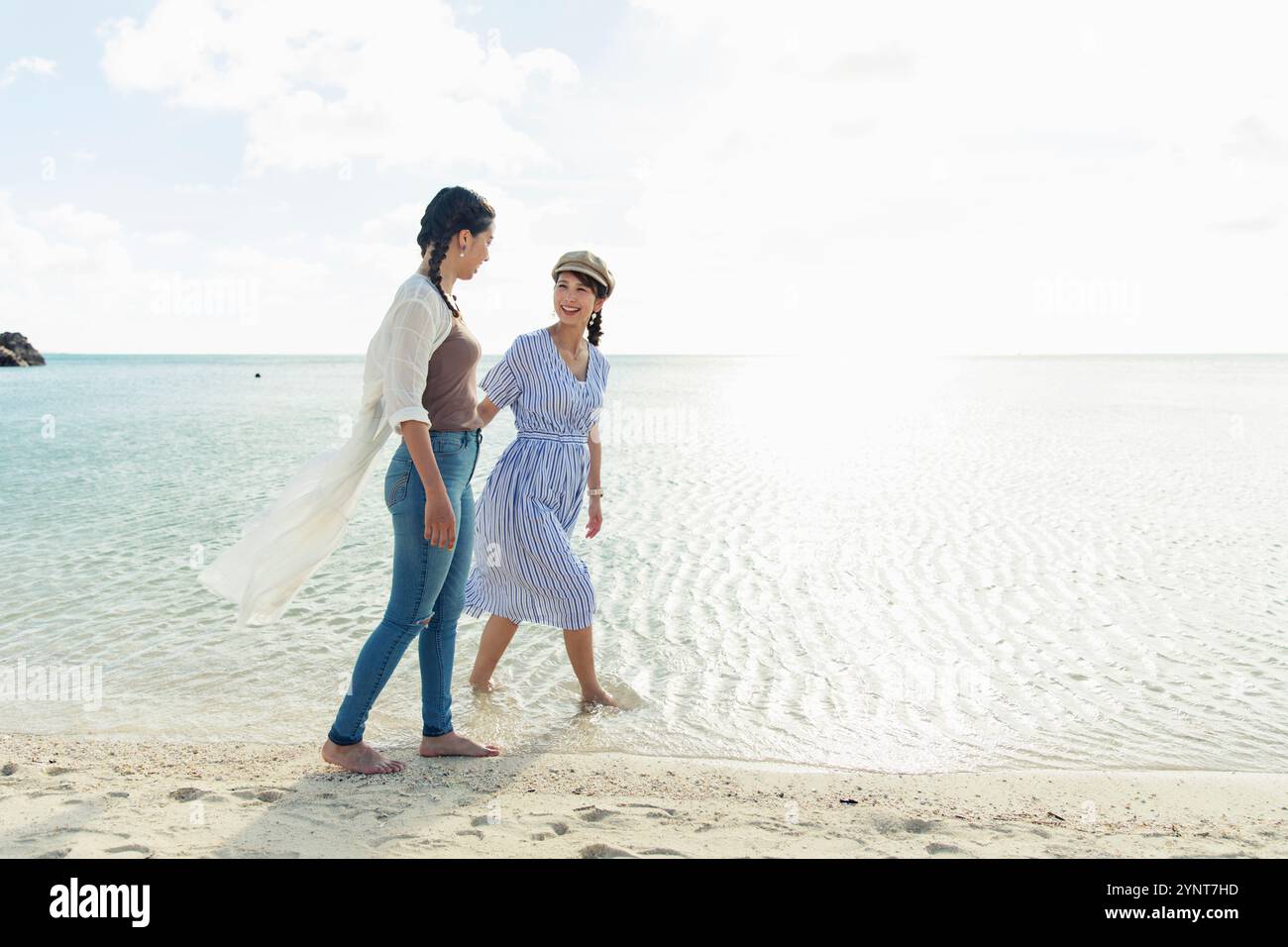 Two women in their 20s walking on a sandy beach Stock Photo - Alamy