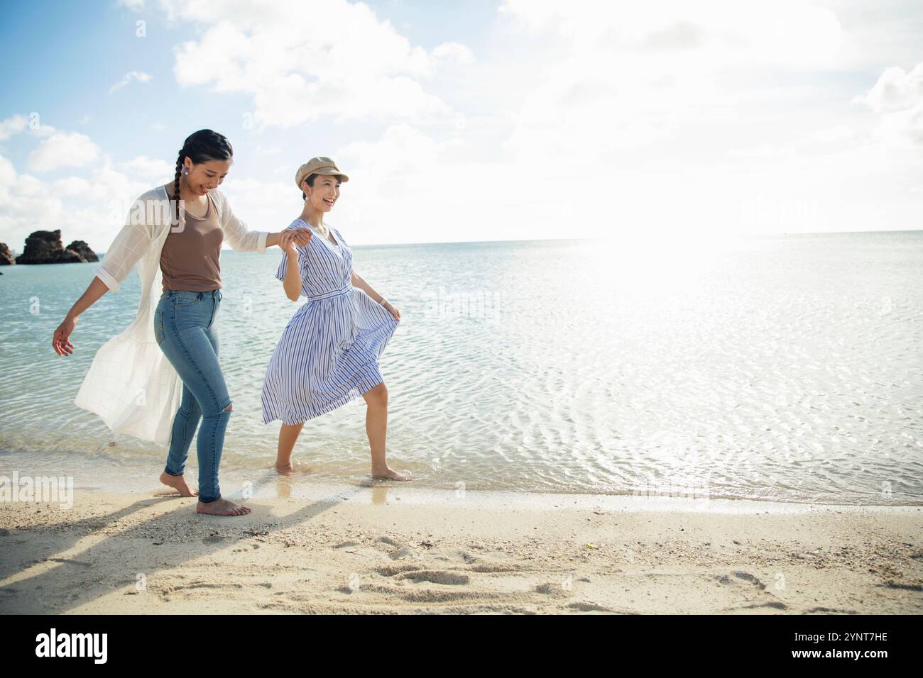 Two women in their 20s walking on a sandy beach Stock Photo - Alamy