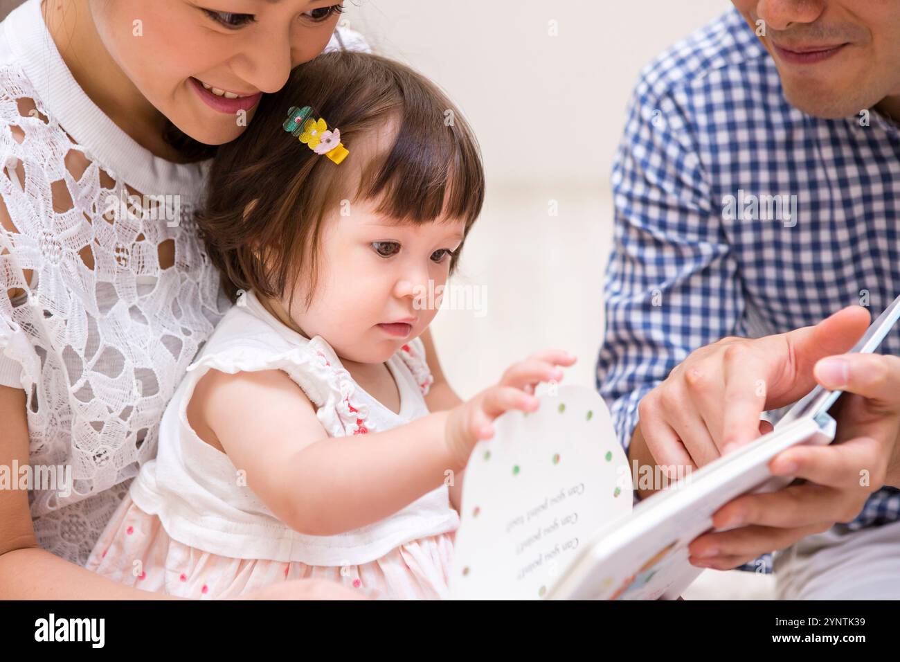 Family reading a book to their child Stock Photo - Alamy
