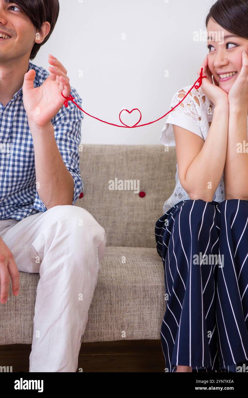 Man and woman connected by red thread Stock Photo - Alamy