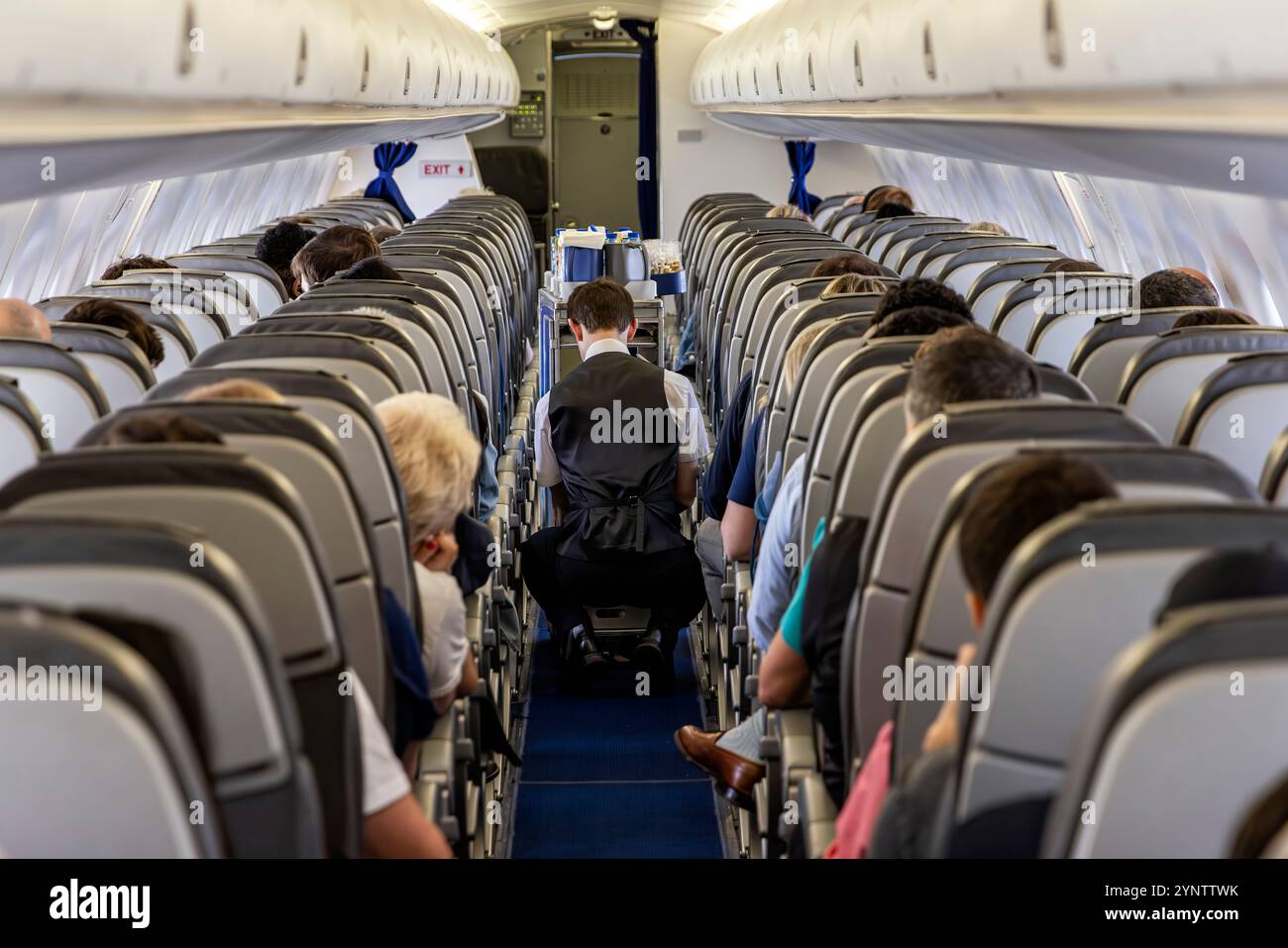 Cabin interior, steward with drinks trolley onboard flight from UK to Amsterdam with KLM Eastern airline Stock Photo