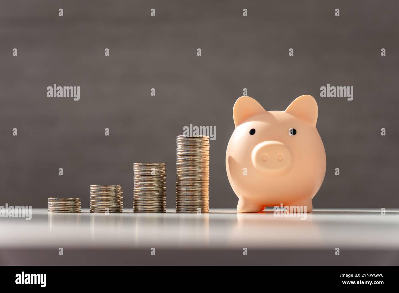 Silver coins stack and pink piggy bank on grey background with growth ...