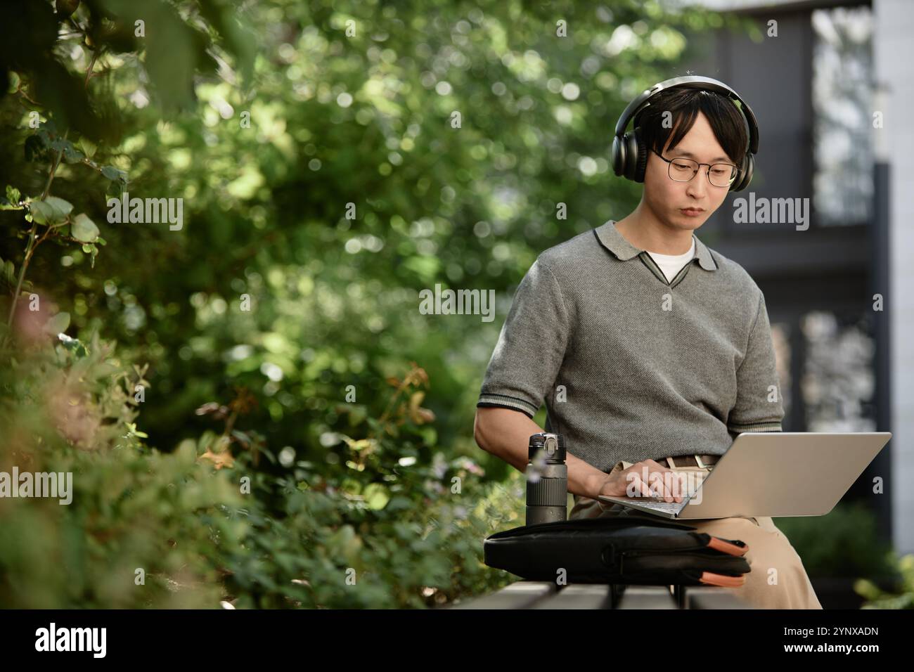 Medium shot of Asian male IT developer concentrated on using laptop to write code Stock Photo