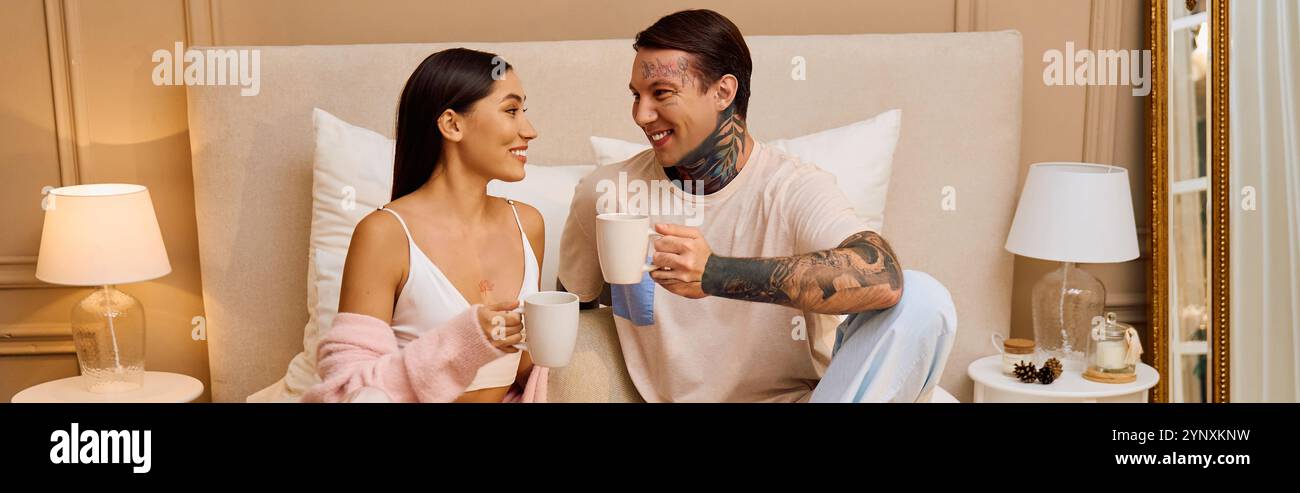 A loving young couple smiles at each other over coffee in a beautifully decorated bedroom. Stock Photo