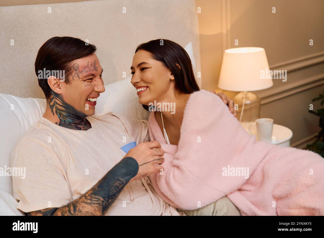 A young couple shares laughter and affection on a blissful evening in their cozy space. Stock Photo