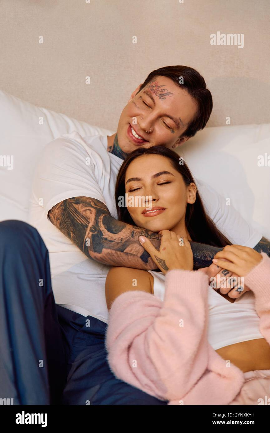 A young couple enjoys a tender moment together on a comfy bed, radiating love and happiness. Stock Photo