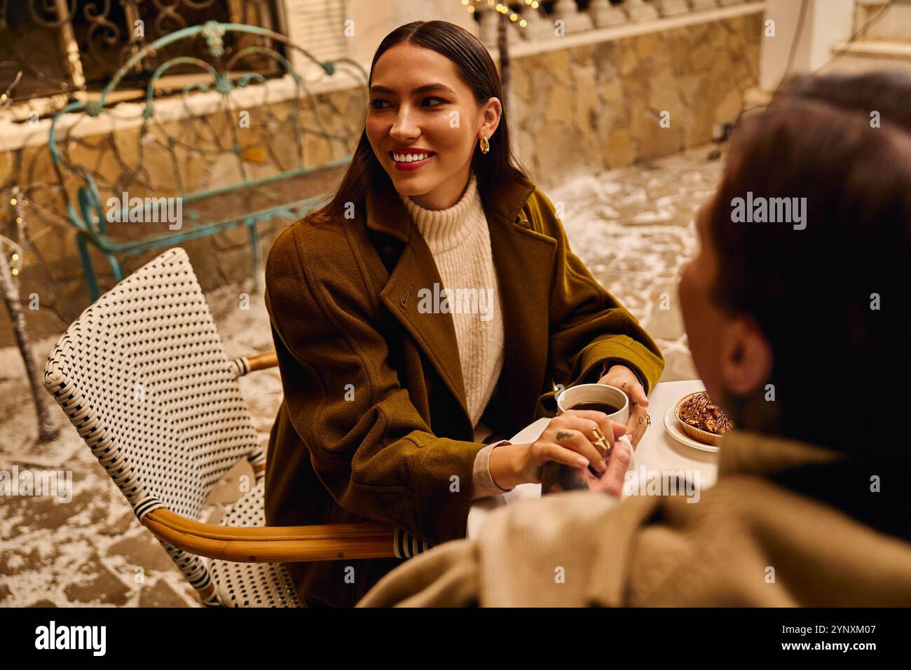 A young couple sits together in a charming cafe, smiling as they connect over hot beverages. Stock Photo