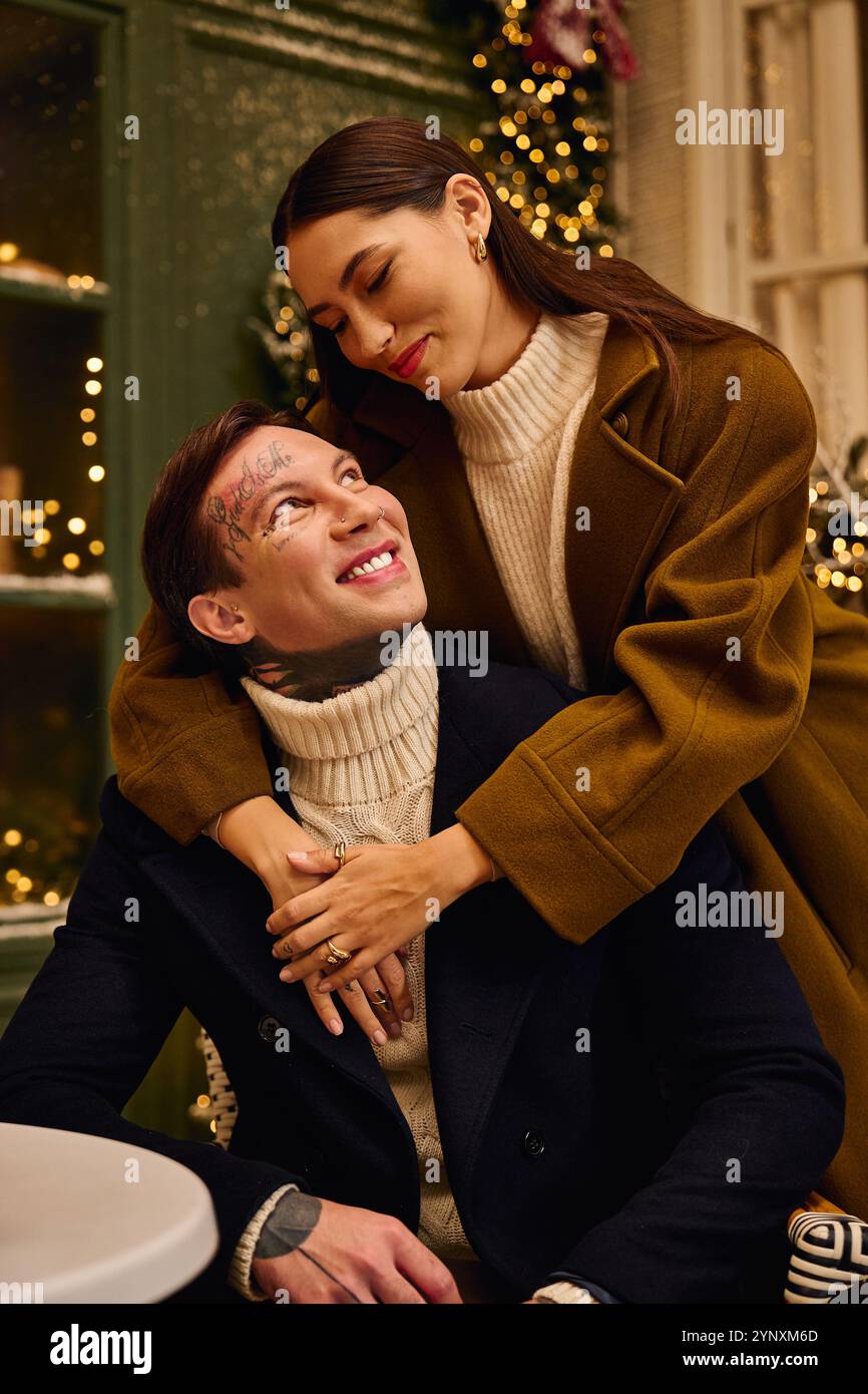 Couple shares a loving glance while seated together at a cozy cafe decorated for winter. Stock Photo