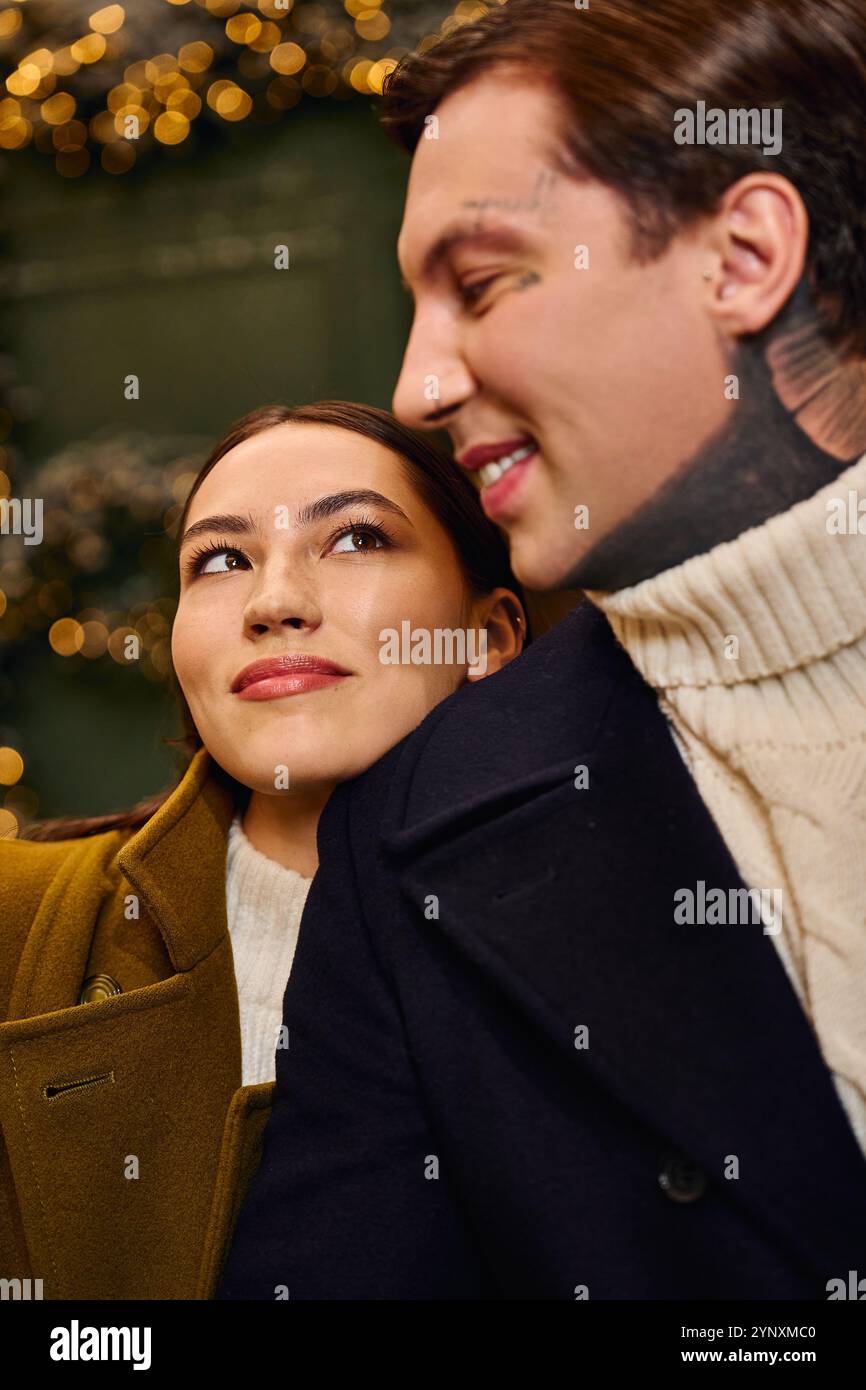 Young pair radiates happiness as they enjoy a warm, intimate moment surrounded by holiday lights Stock Photo