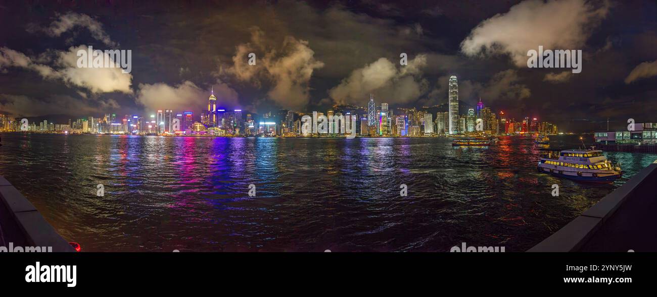 Panoramic nighttime view of illuminated Hong Kong skyline reflected in the water with vibrant city lights in summer Stock Photo