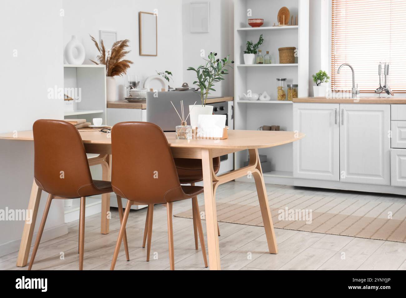 Interior of light kitchen with laptop on dining table, counters and ...