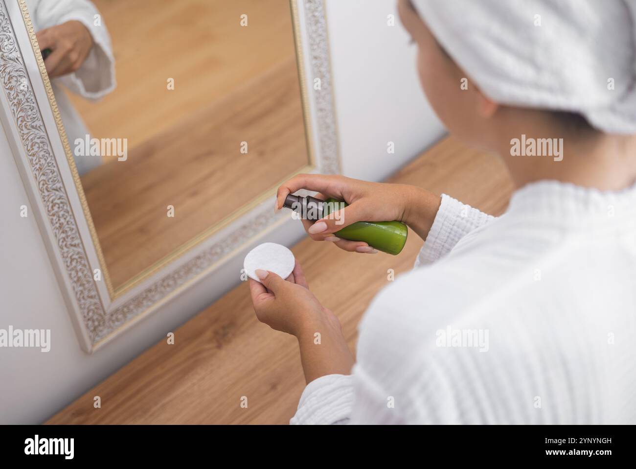 woman attentively incorporates cleansing lotion into her skincare regimen using a cotton pad  Stock Photo