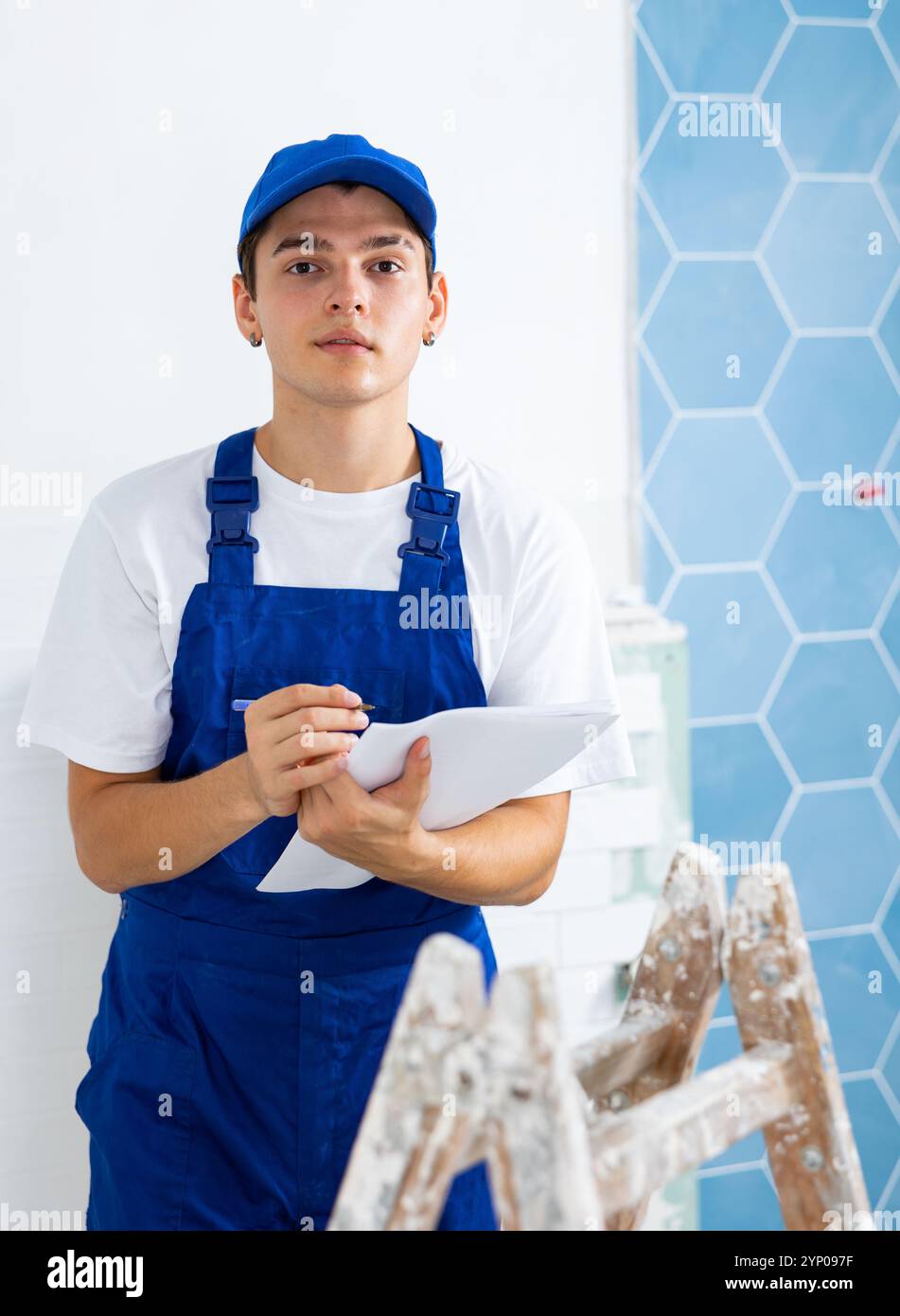 Focused contractor taking notes while planning renovation works in building Stock Photo