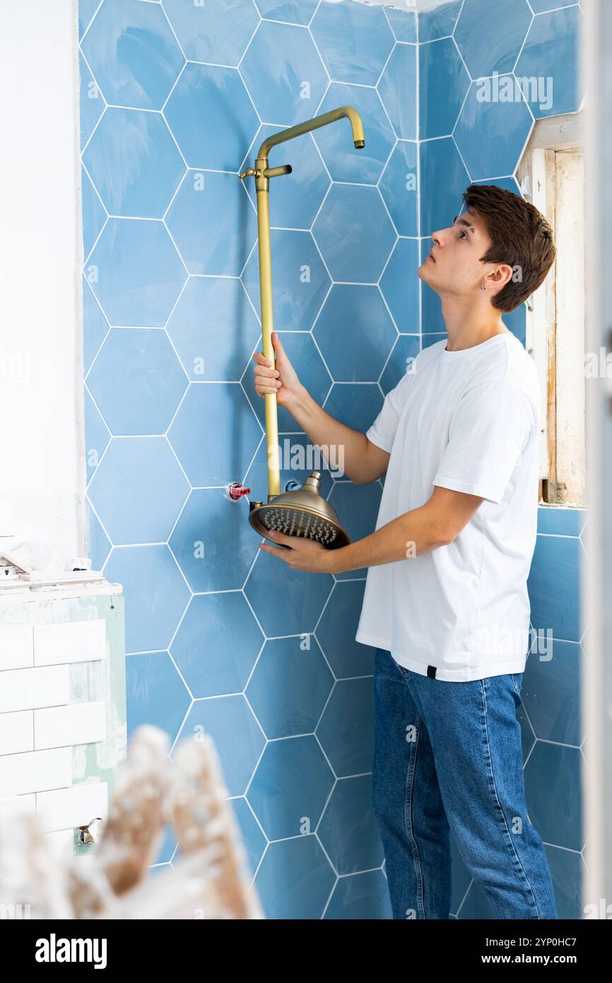 Focused guy assembling shower set before fixing to wall Stock Photo