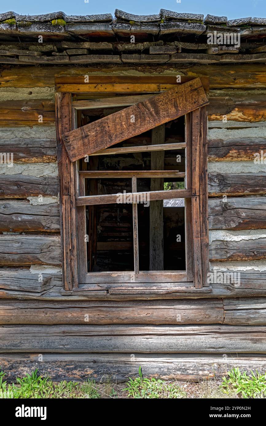 A partially boarded window frame of an abandoned log cabin Stock Photo ...
