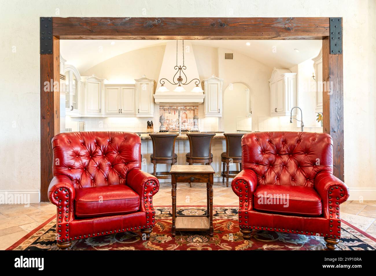 Cozy living area with elegant red chairs and a spacious kitchen in view Stock Photo