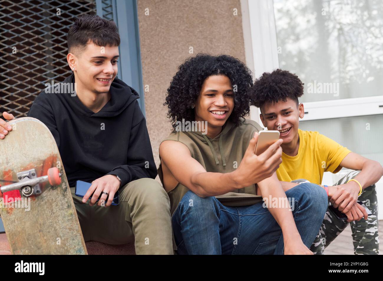 teen friends sharing mobile phone sitting together Stock Photo