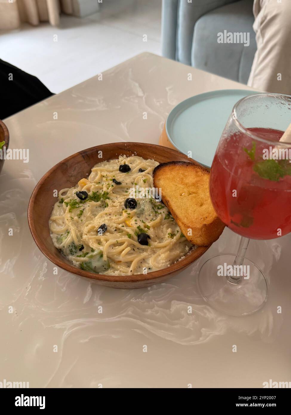 Spaghetti bowl with garlic bread on a table with a glass of mojito. - Smartphone Captured Stock Image