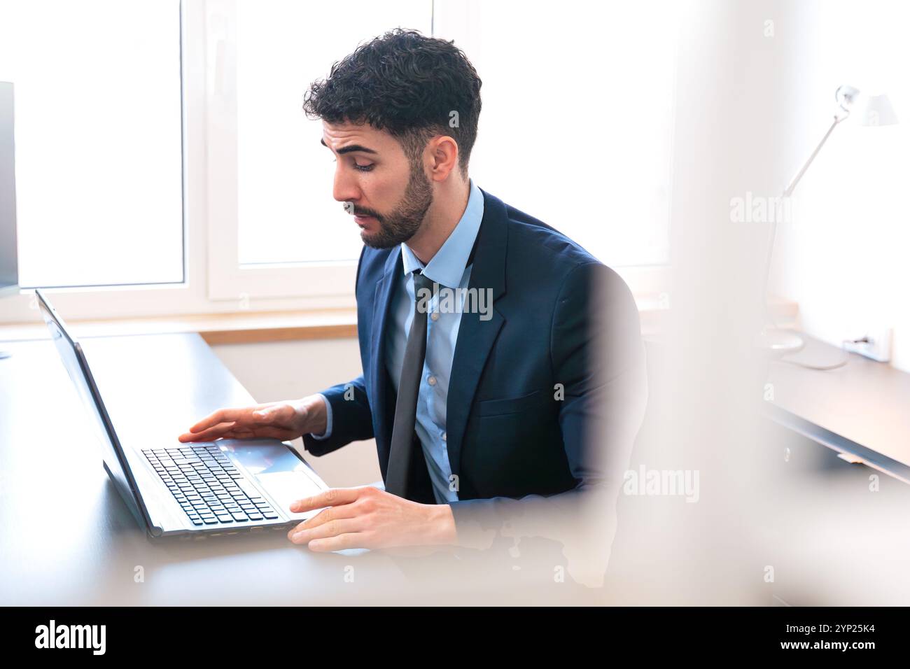Businessman working on laptop in modern office during working hours. Stock Photo