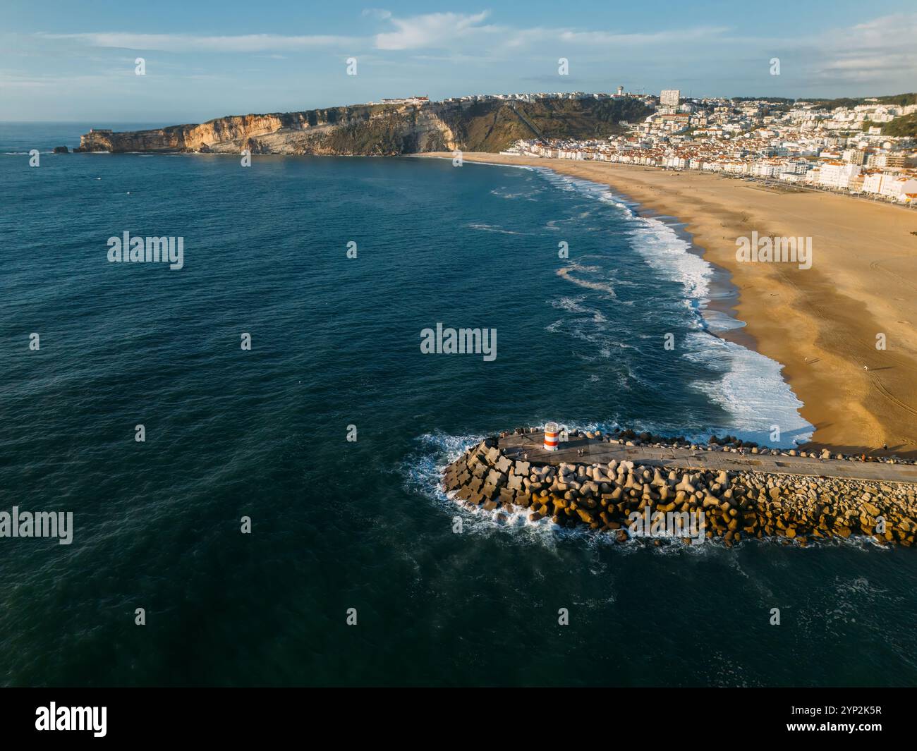 Aerial drone view of Nazare coastline showcasing beautiful beach, vibrant surf and rocky pier, Nazare, Oeste, Estremadura, Portugal, Europe Stock Photo