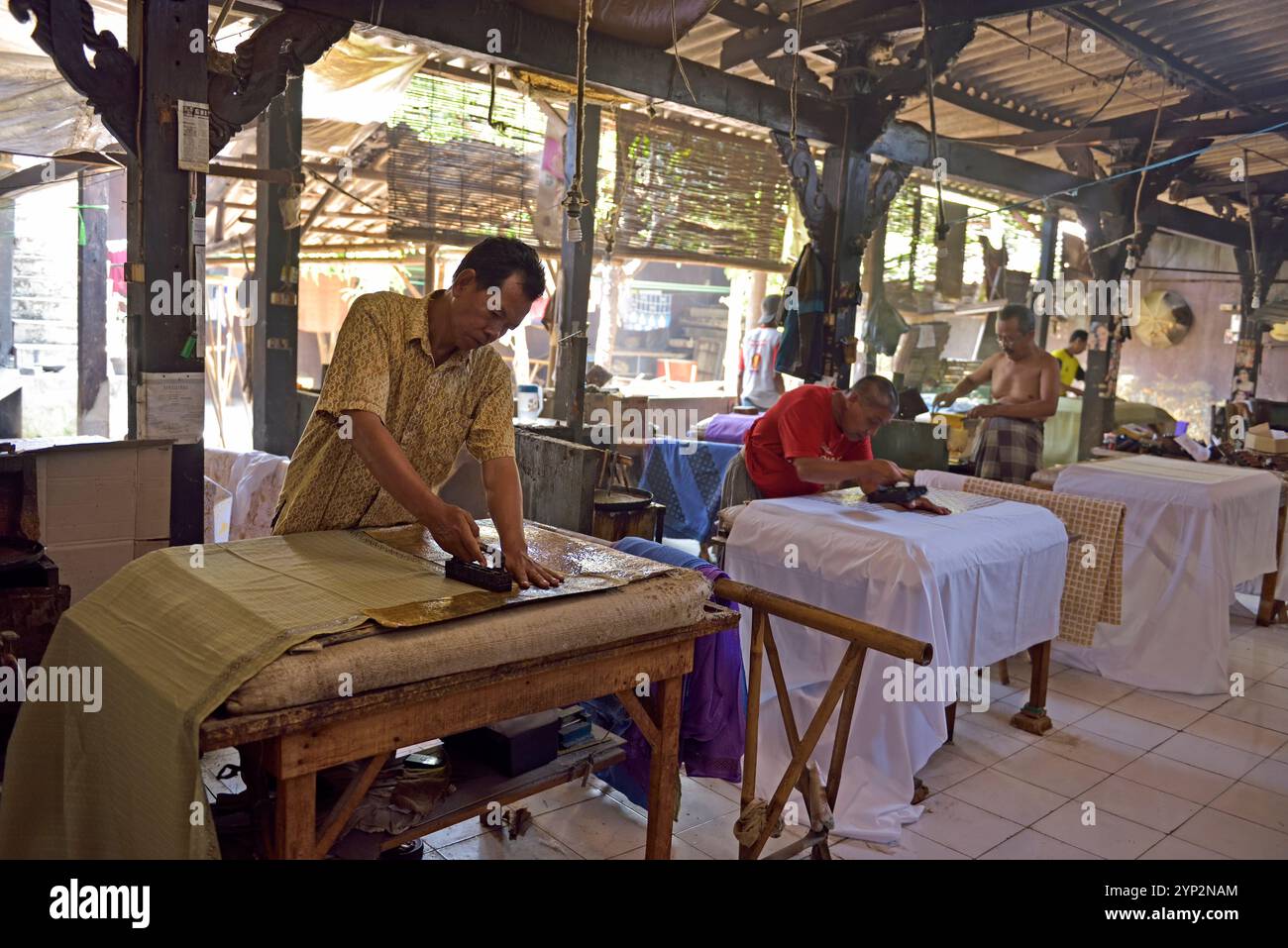 Workers applying wax-resist using a copper plate stamp (cap), Wirakuto batik workshop, Pekalongan, Java island, Indonesia, Southeast Asia, Asia Stock Photo