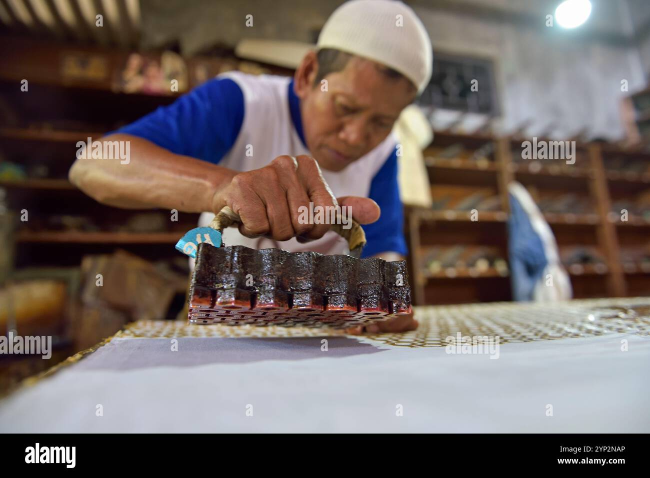 Workers applying wax-resist using a copper plate stamp (cap), Wirakuto batik workshop, Pekalongan, Java island, Indonesia, Southeast Asia, Asia Stock Photo