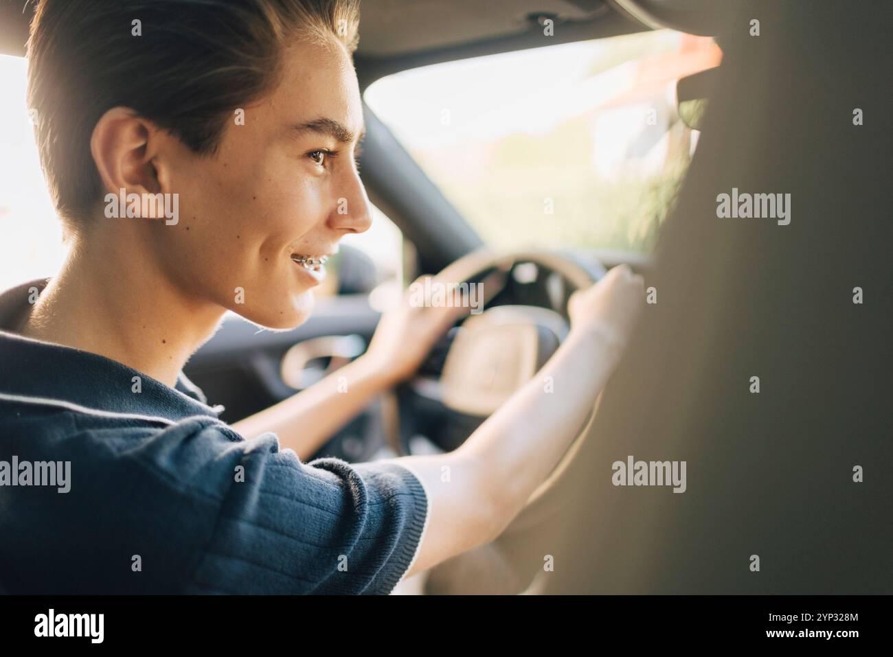 Side view of smiling teenage boy driving car Stock Photo - Alamy