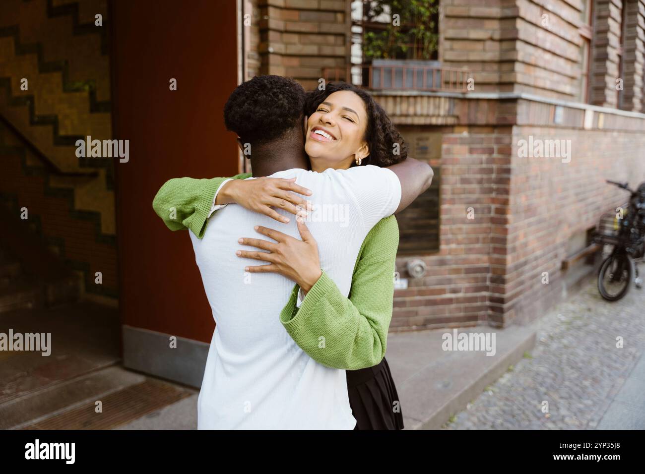 Happy young woman embracing boyfriend while standing near building Stock Photo
