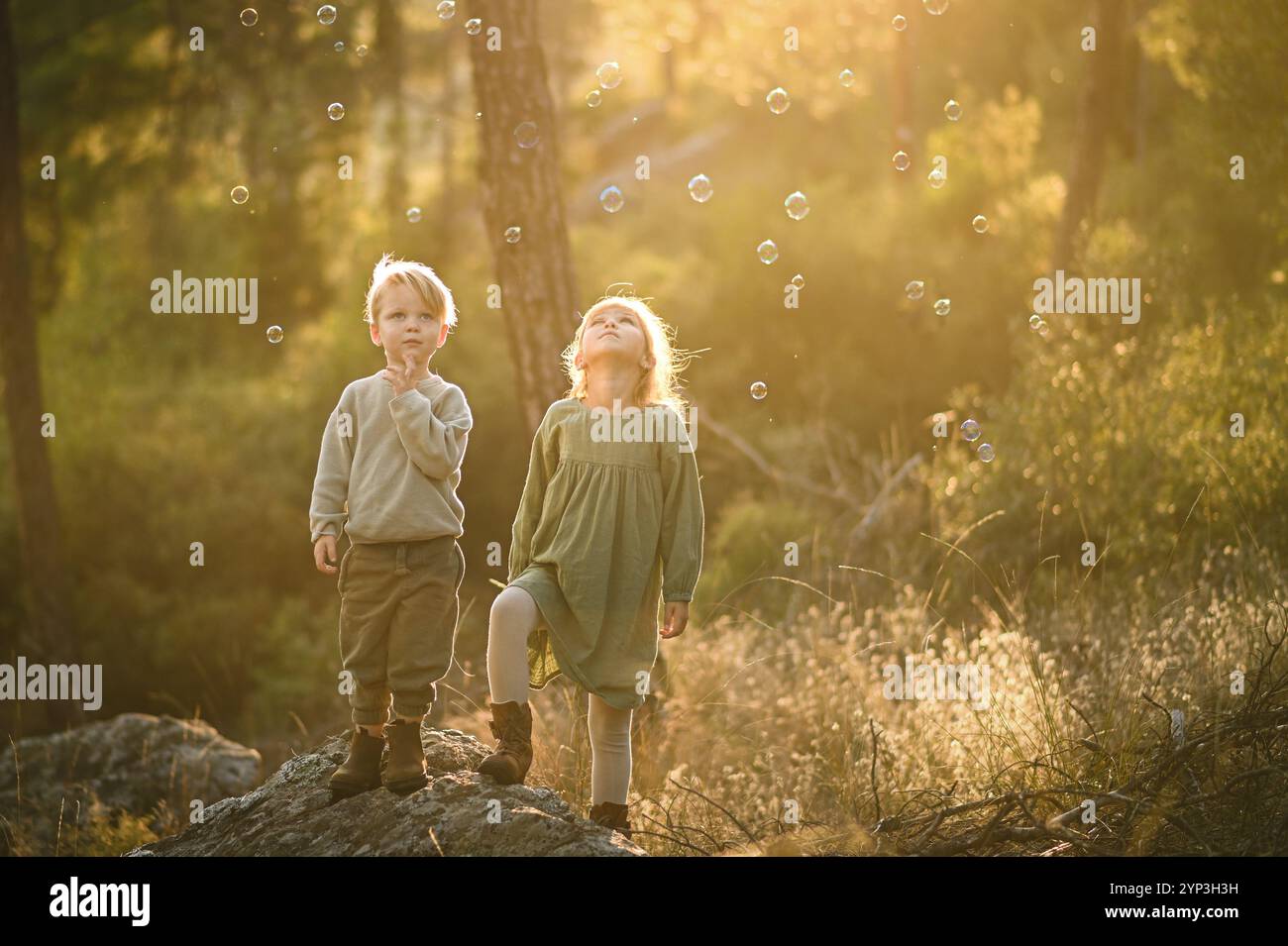 girl and boy in a magic forest with bubbles Stock Photo