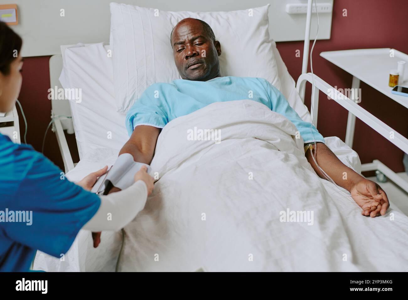 I Using Hospital Senior Black man in a hospital bed receiving medical care with ...