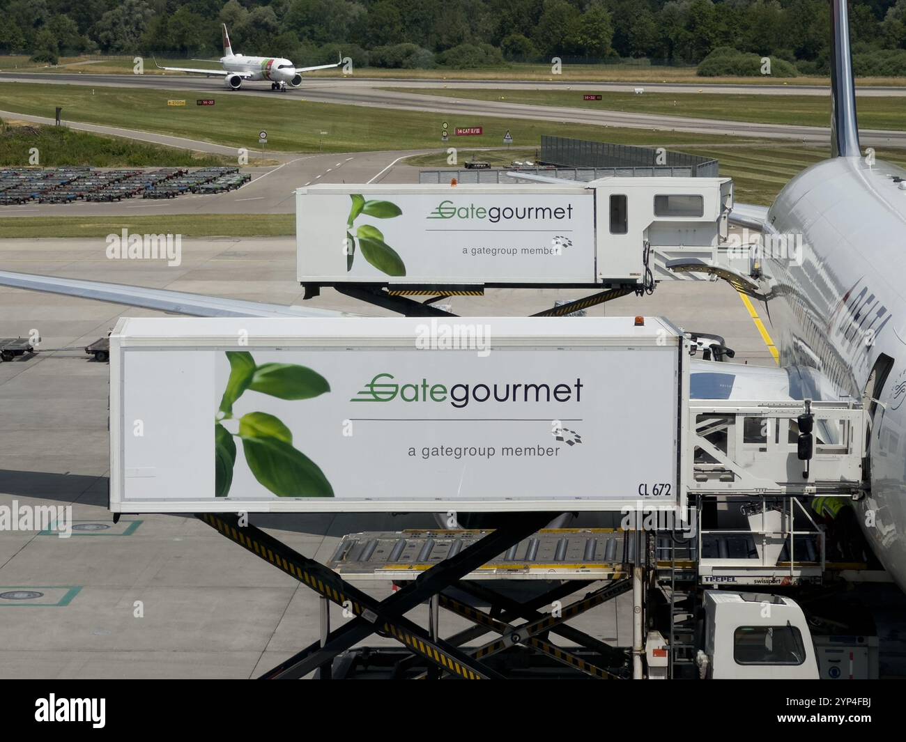 Zurich, Switzerland - June 28, 2023: Two Gategourmet trucks are shown next to a Delta aircraft, loading prepared meals for a long-haul flight. - Smartphone Captured Stock Image