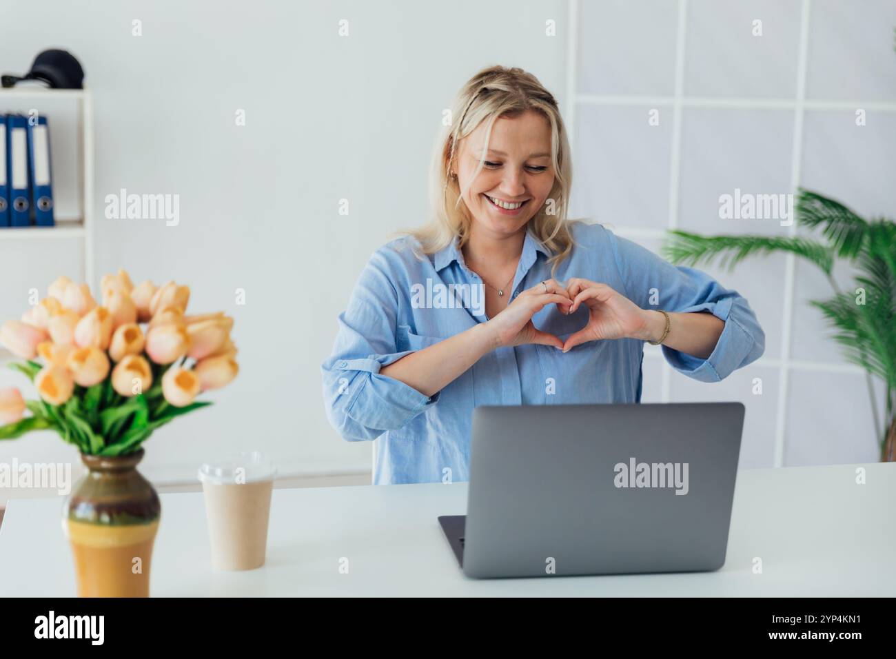 Business blonde woman with laptop online smiling and showing her hands ...