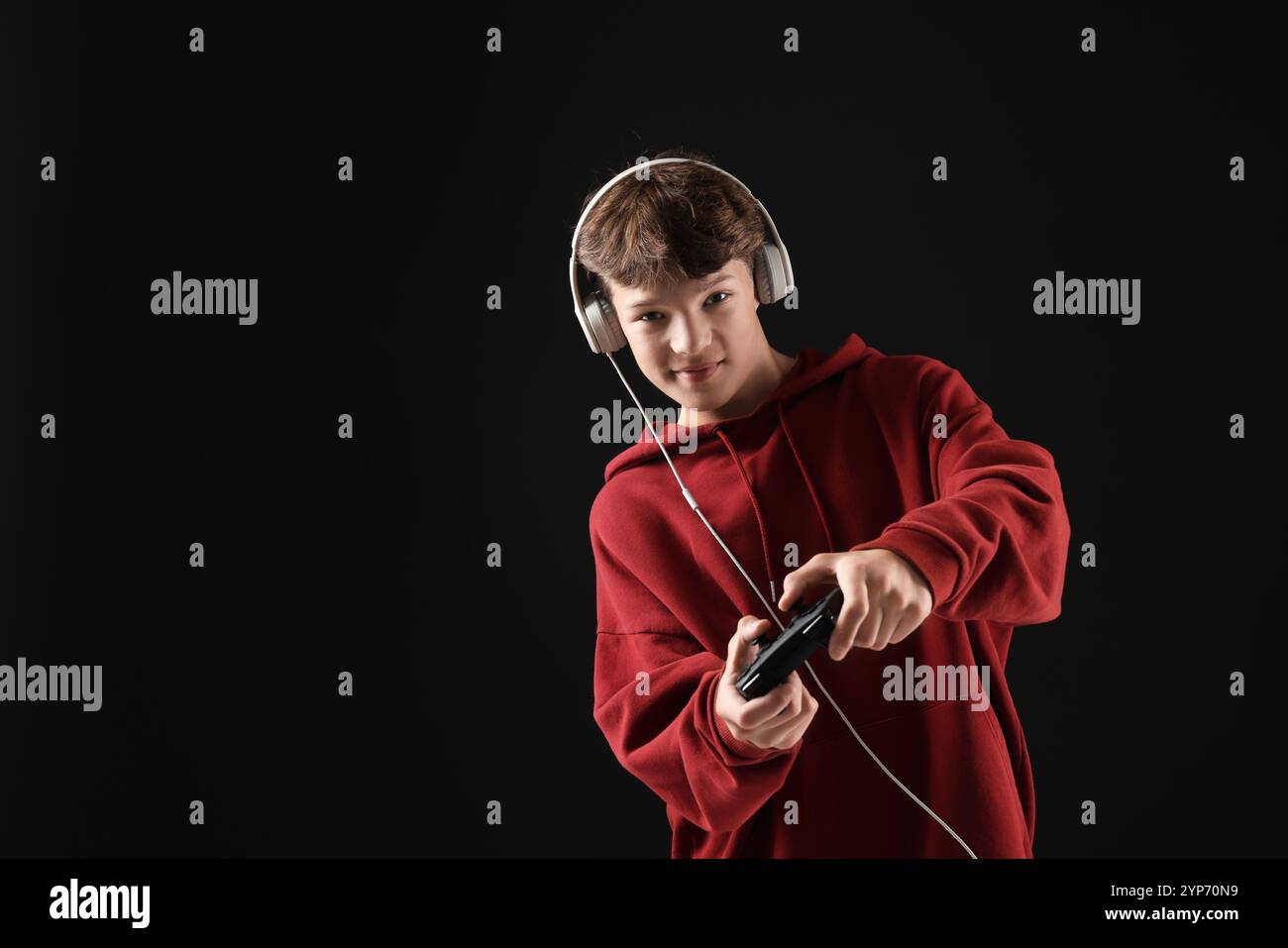 Teenage boy in headphones playing video game with controller on black ...