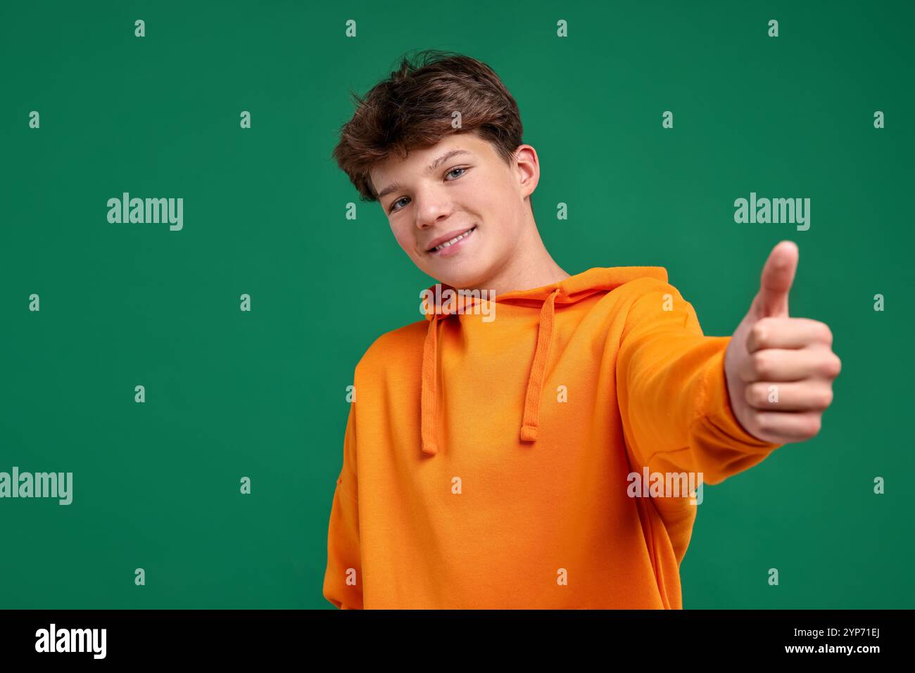 Happy teenage boy showing thumbs up on green background Stock Photo - Alamy