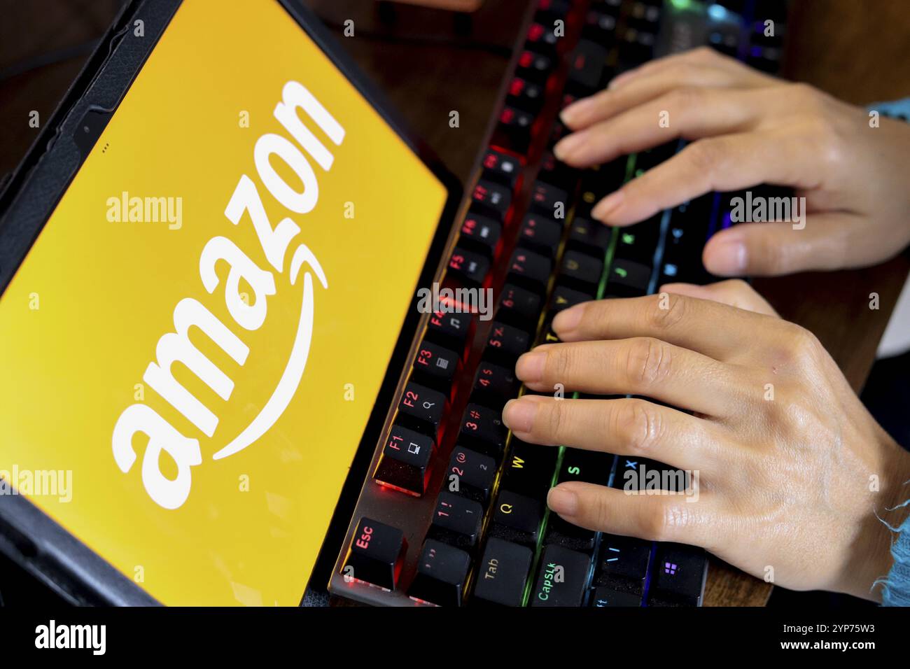 In this photo illustration, a person typing and next to the Amazon logo ...