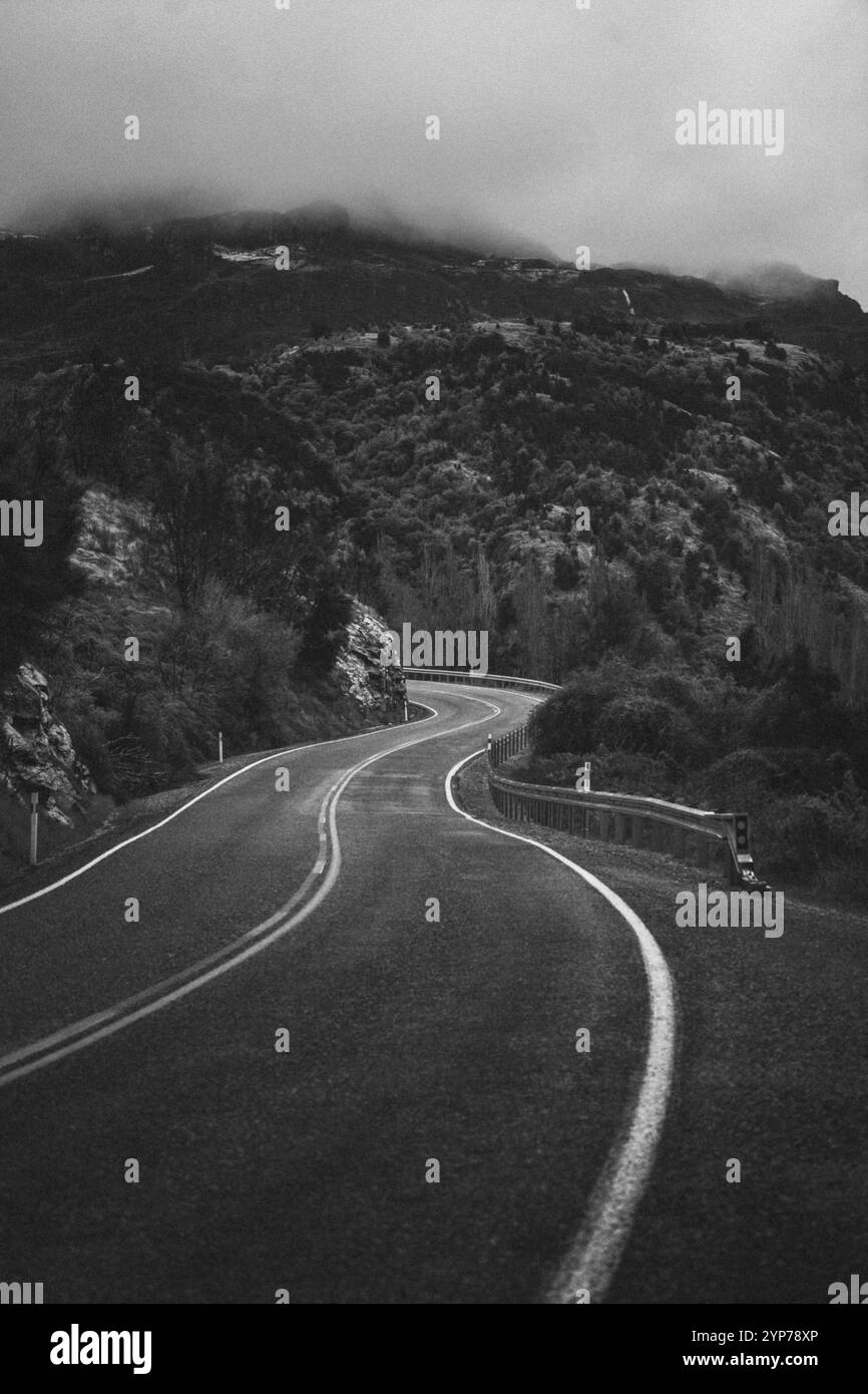 A winding road through misty mountains in a lonely, gloomy black and ...
