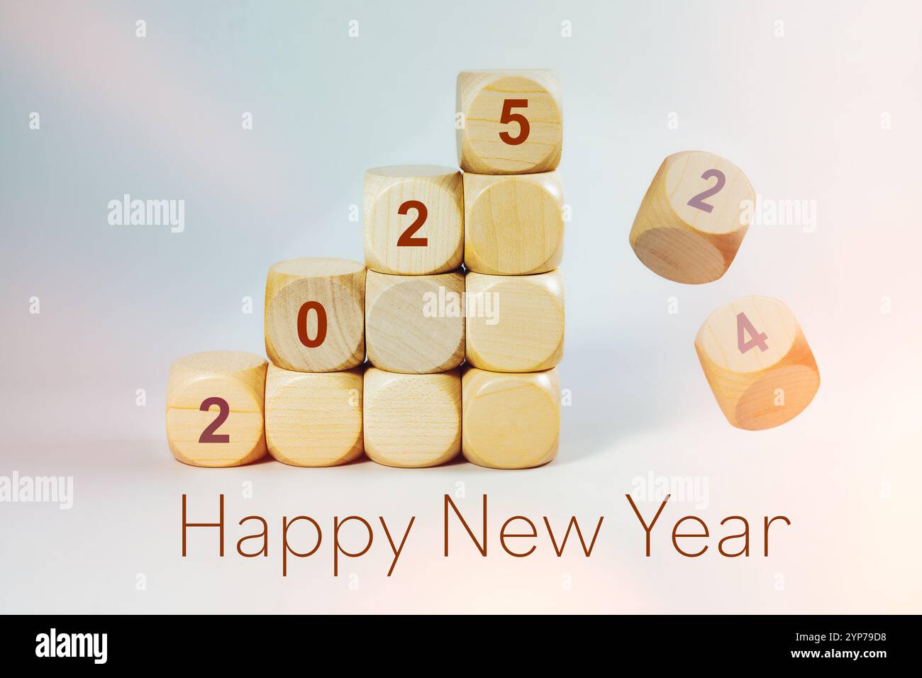 Happy new year 2025, the number is written on stacked wooden cubes,  the old numbers are falling down, light background, copy space Stock Photo
