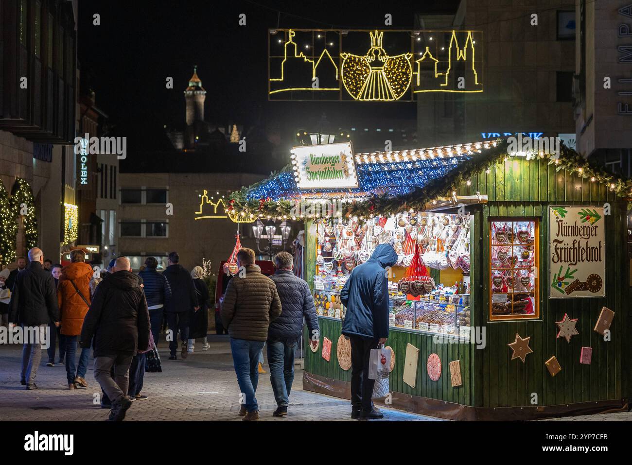 Weihnachtliche Nürnberger Fußgängerzone, 28.11.204 Ein Süßigkeitenstand in der Königstraße zwischen dem Lorenzerplatz und dem Hauptmarkt, wo der Christkindlesmarkt stattfindet. Über dem Stand hängt eine Lichterkette in Form des Nürnberger Rauschengels. Im Hintergrund erhebt sich der Sinwellturm der Kaiserburg, beleuchtet in der winterlichen Nacht. Nürnberg Bayern Deutschland *** Nurembergs Christmas pedestrian zone, 28 11 204 A candy stand in Königstrasse between Lorenzerplatz and the main market square, where the Christmas market takes place A string of lights in the shape of the Nuremberg Ra Stock Photo