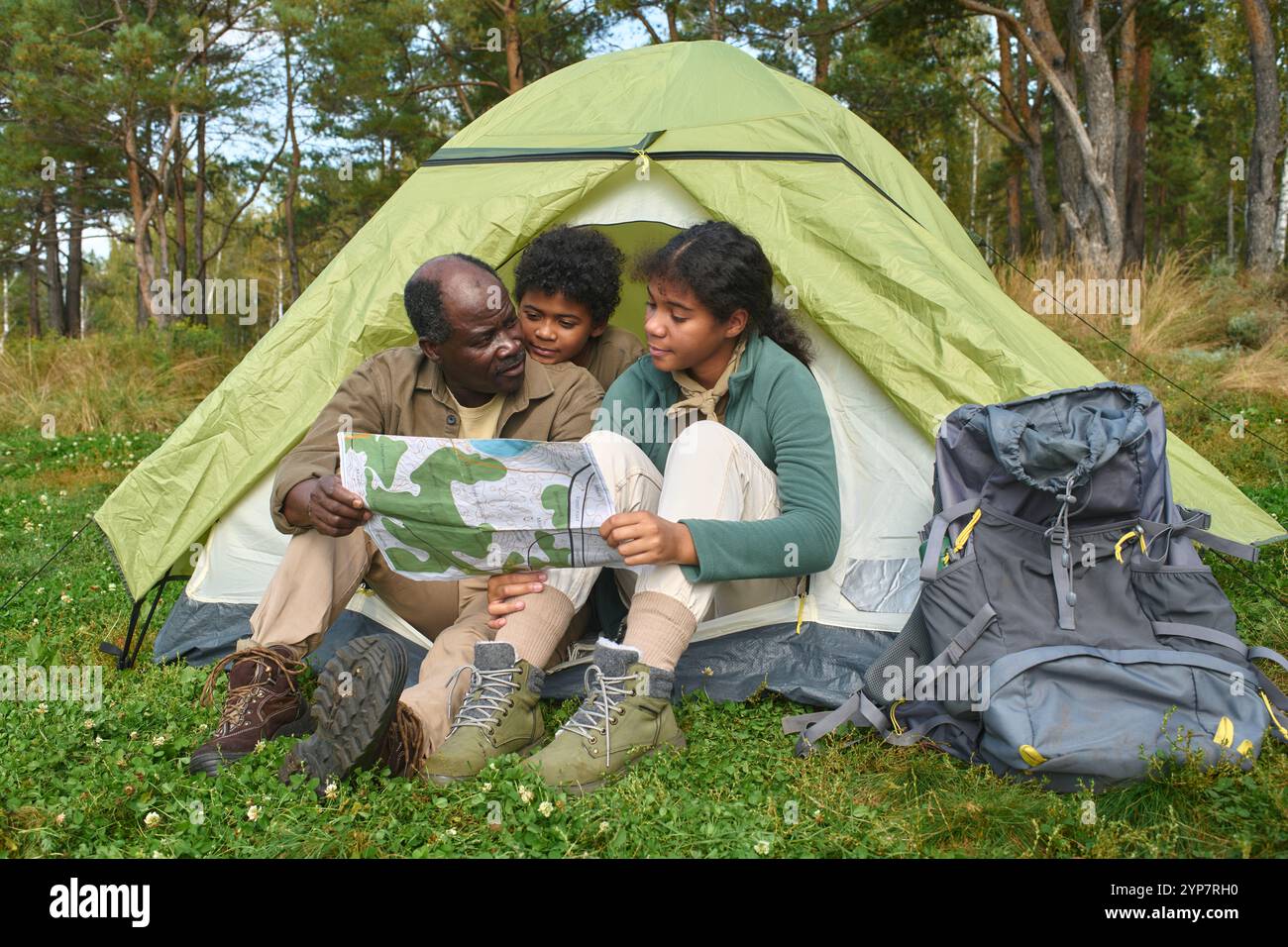 African American father holding map in hands while discussing next area ...