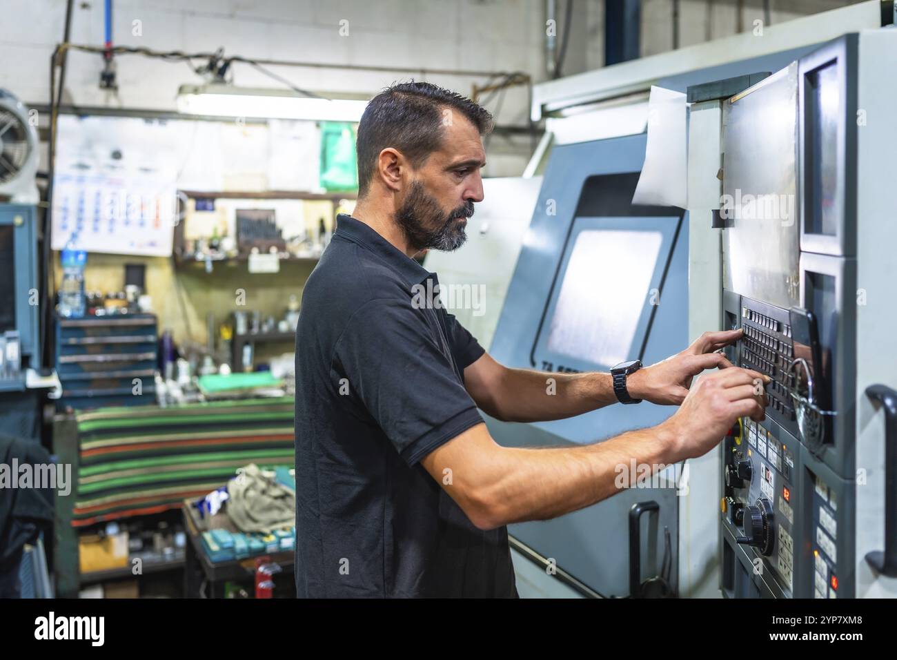 Mature man working on control panel of a lathe in cnc factory Stock ...