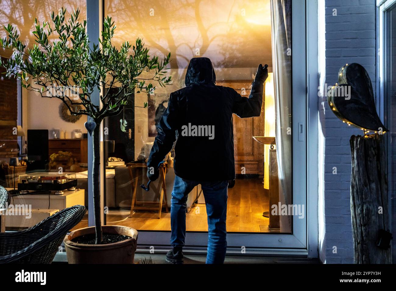 Symbolic image of a burglary, perpetrator spying on an apartment from the garden side, Stock Photo