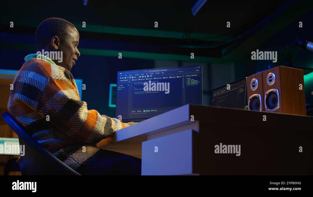 Black software engineer writes complex binary code scripts on computer, cybersecurity. Teleworking IT specialist in home office using programming language to safeguard consumer data. Camera B. Stock Photo